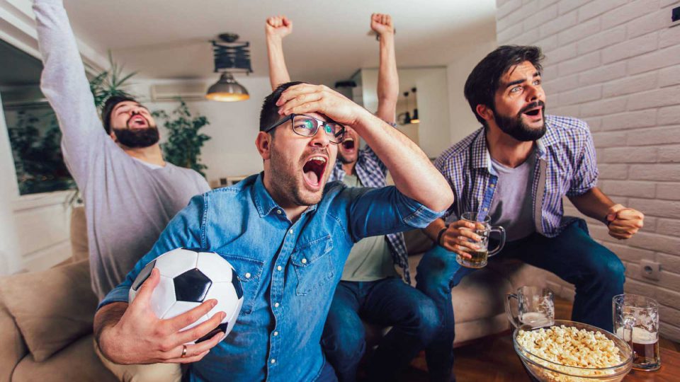 Freunde schauen gemeinsam Fußball und jubeln