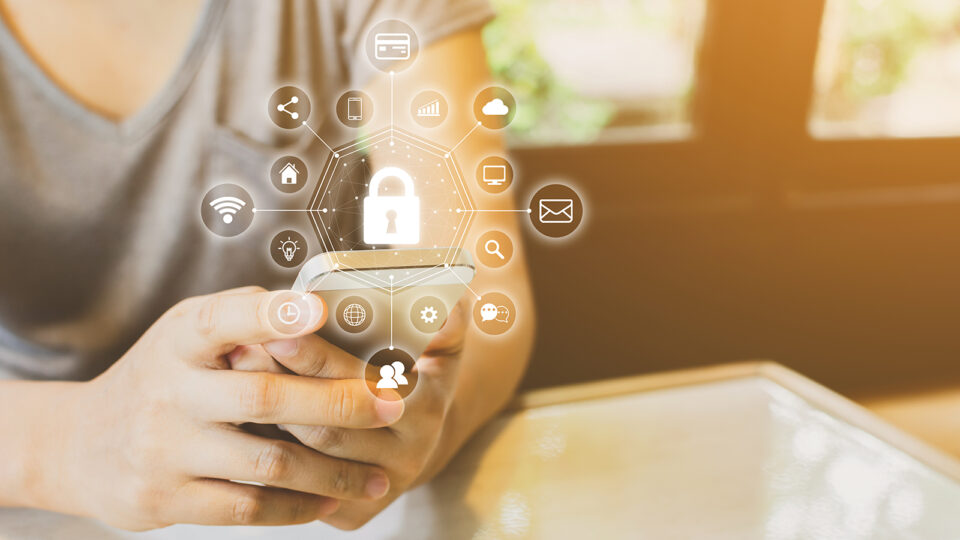 Jemand hält ein Smartphone in der Hand. Ein Piktogramm visualisiert Sicherheit im Netz.