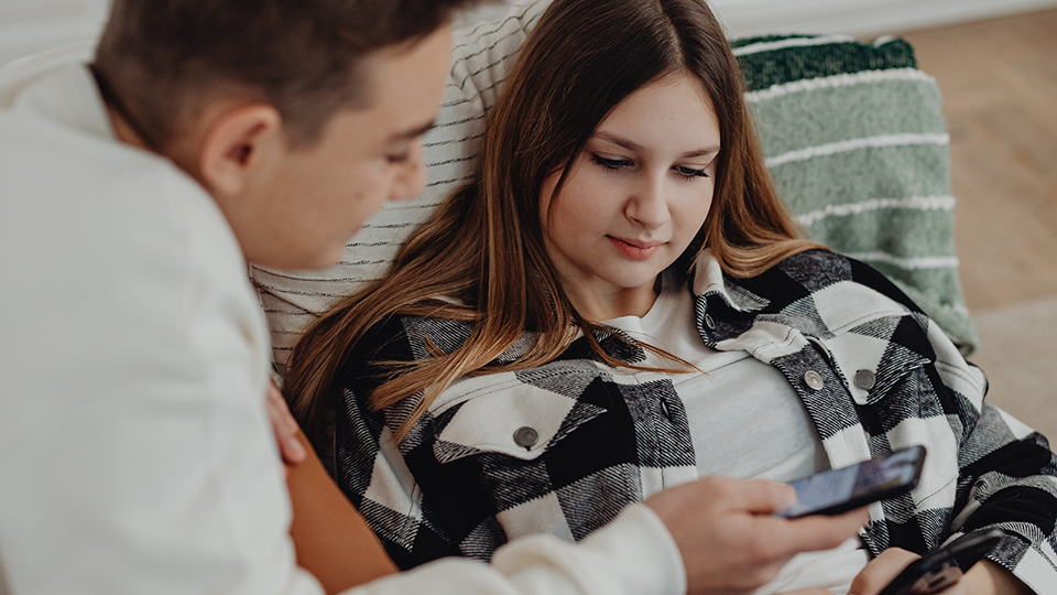 Junger Mann und junge Frau schauen auf Smartphone
