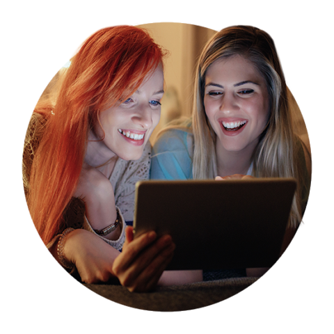 Zwei Freundinnen lachen vor Tablet